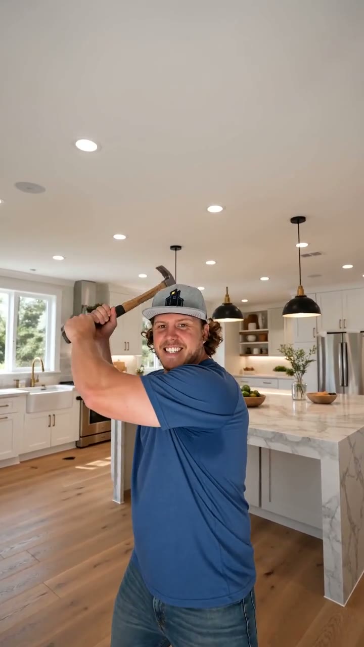 Nate Algar with a hammer in a finished white kitchen